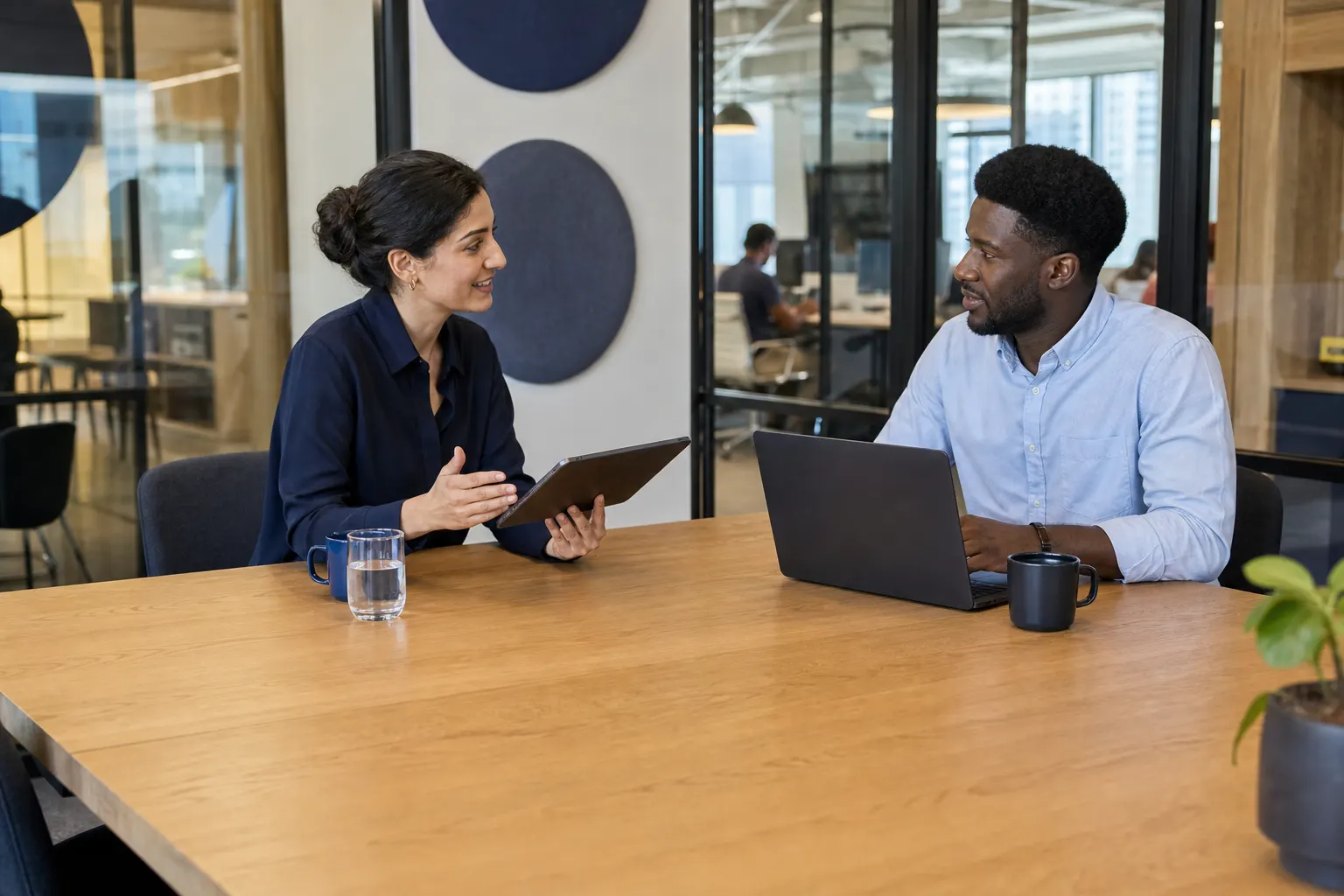 An independent consultant and client using a tablet and laptop in a coworking project room