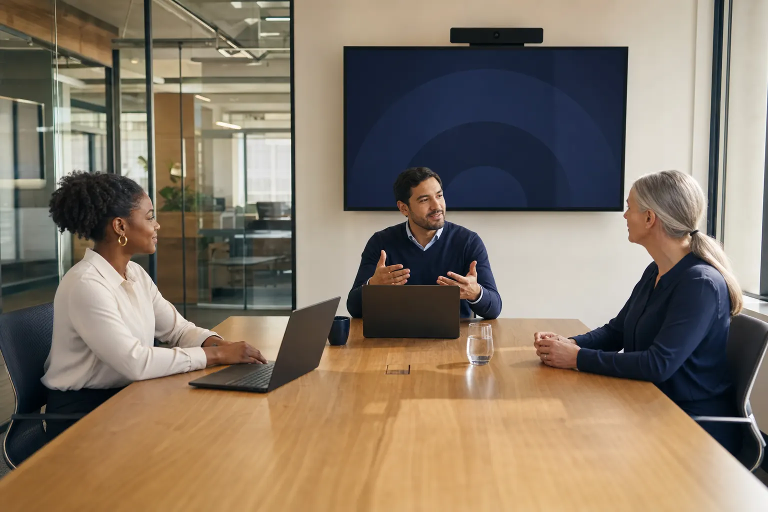 A candidate, recruitment consultant, and hiring manager meeting in a video-enabled conference room
