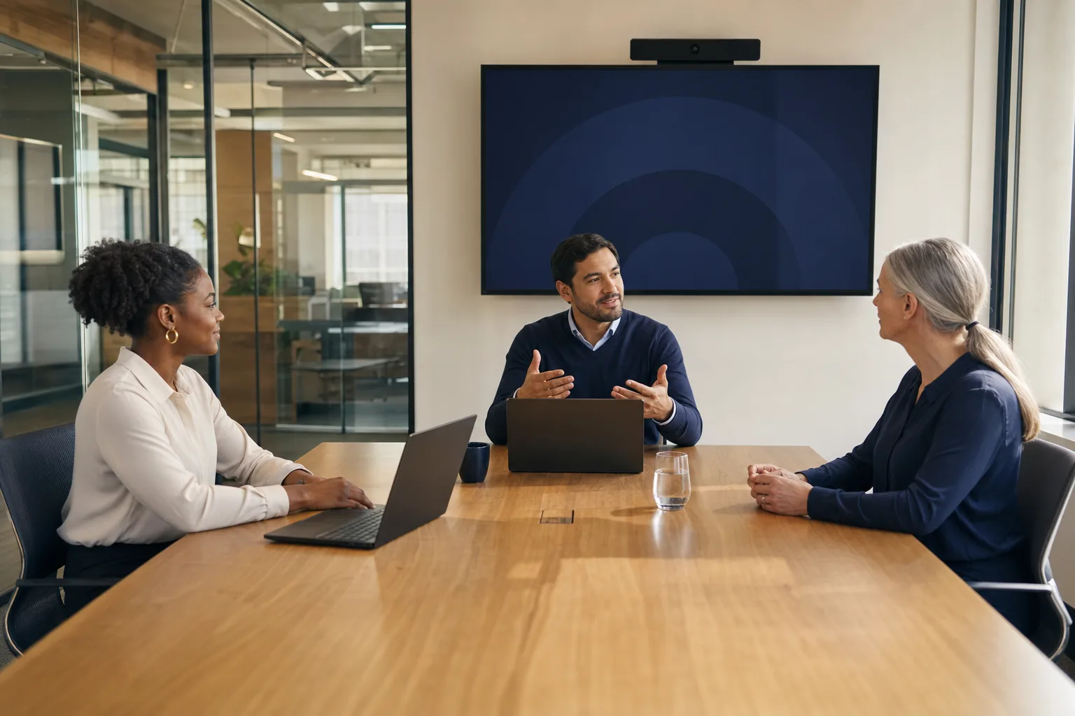 A candidate, recruitment consultant, and hiring manager meeting in a video-enabled conference room